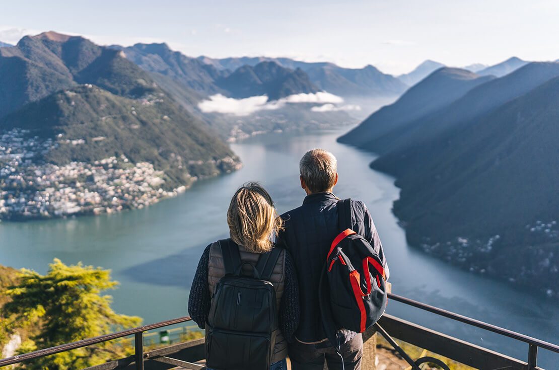 Senior couple walk up to high view point over lake